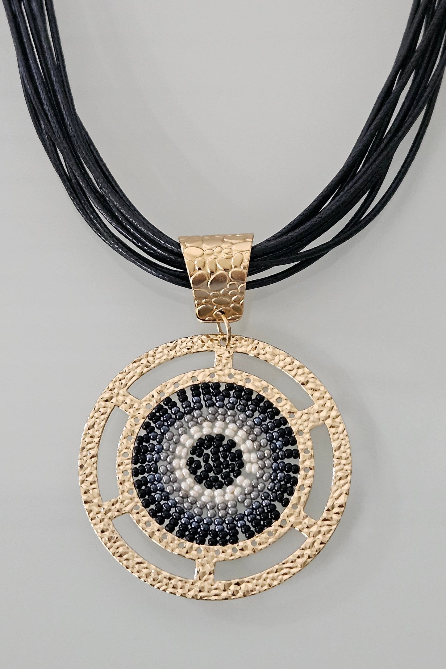 COLLAR NEGRO EN PIEL CON PENDANT REDONDO DORADO, NEGRO, GRIS Y BLANCO