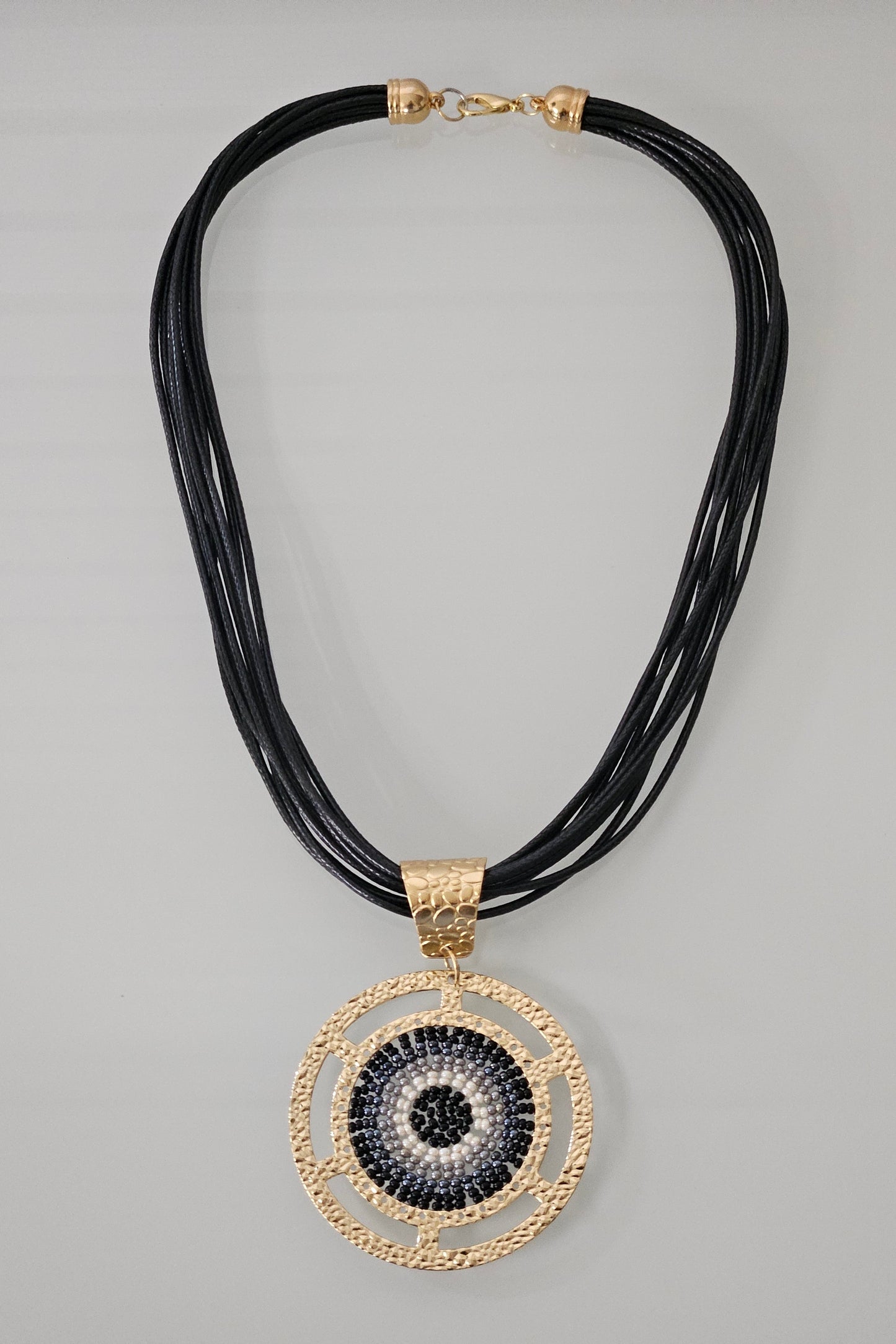 COLLAR NEGRO EN PIEL CON PENDANT REDONDO DORADO, NEGRO, GRIS Y BLANCO