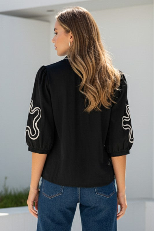 BLUSA NEGRA CON APLIQUES ABSTRACTOS Y MANGAS 3/4