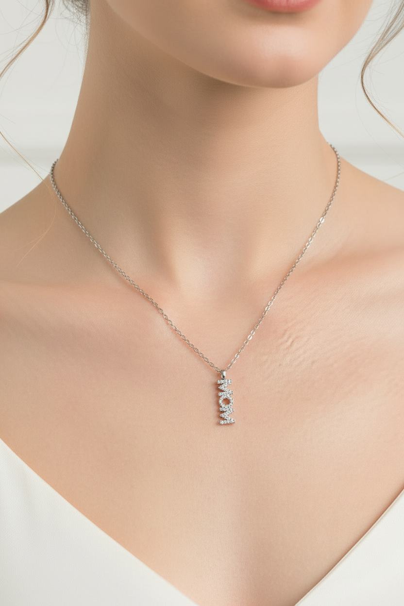Close-up de cadena con dije vertical de MOM en cuello de modelo