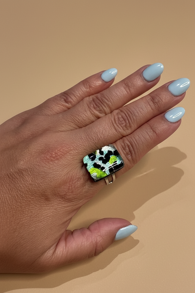 Mano de modelo con anillo verde fondo nude
