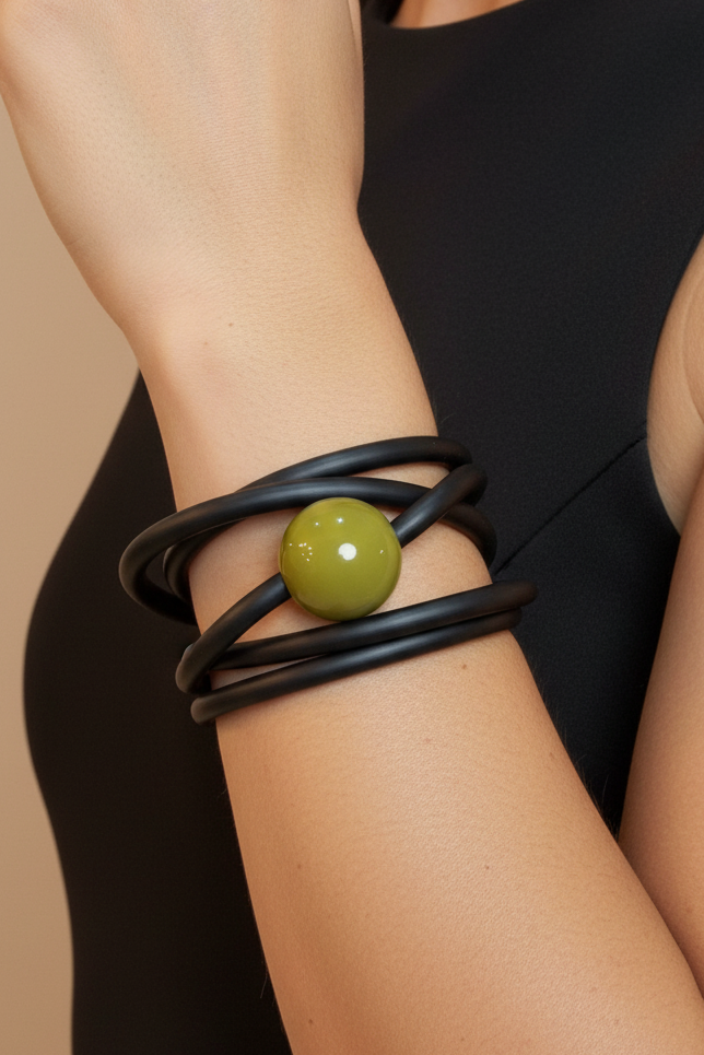 Pulsera negra bead verde en brazo con outfit negro fondo nude