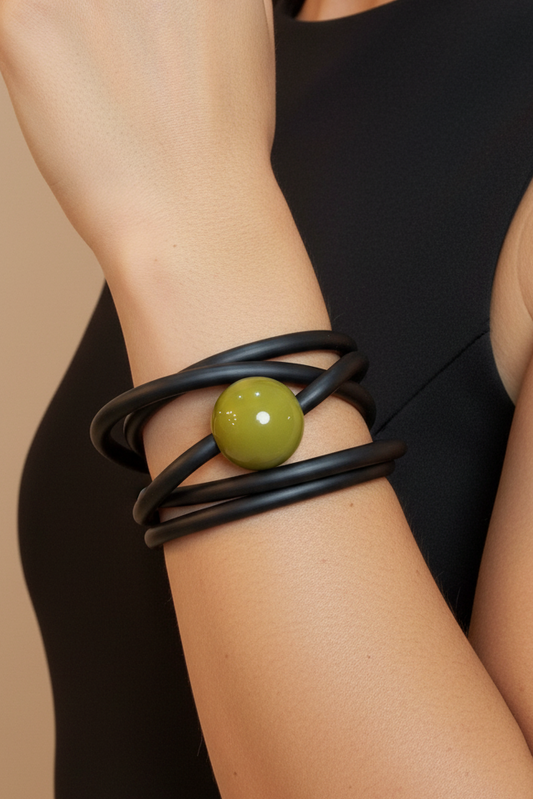 Pulsera negra bead verde en brazo con outfit negro fondo nude